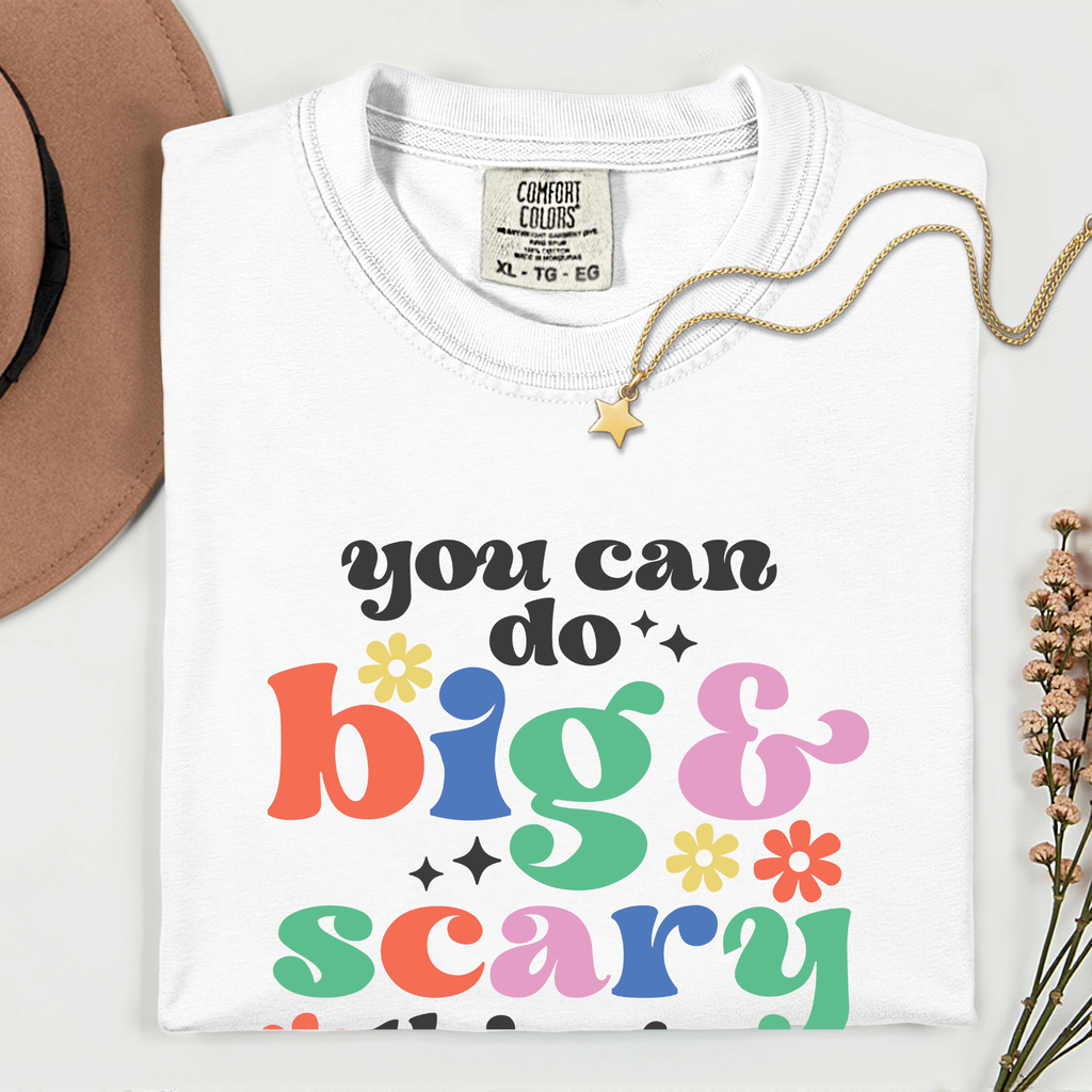White t-shirt with colorful text 'you can do big & scary' on a white background
