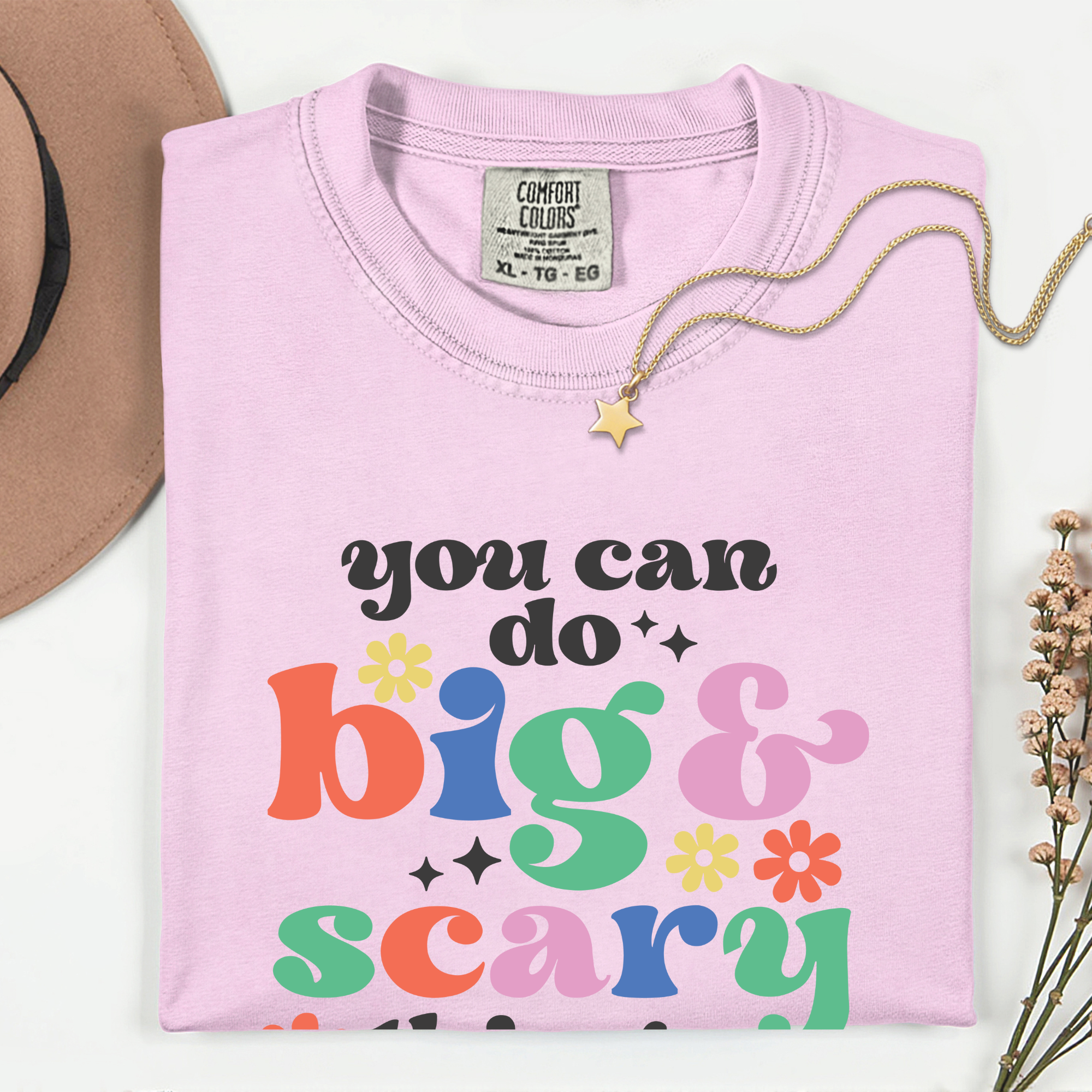Pink shirt with colorful text 'you can do big & scary' on a white background