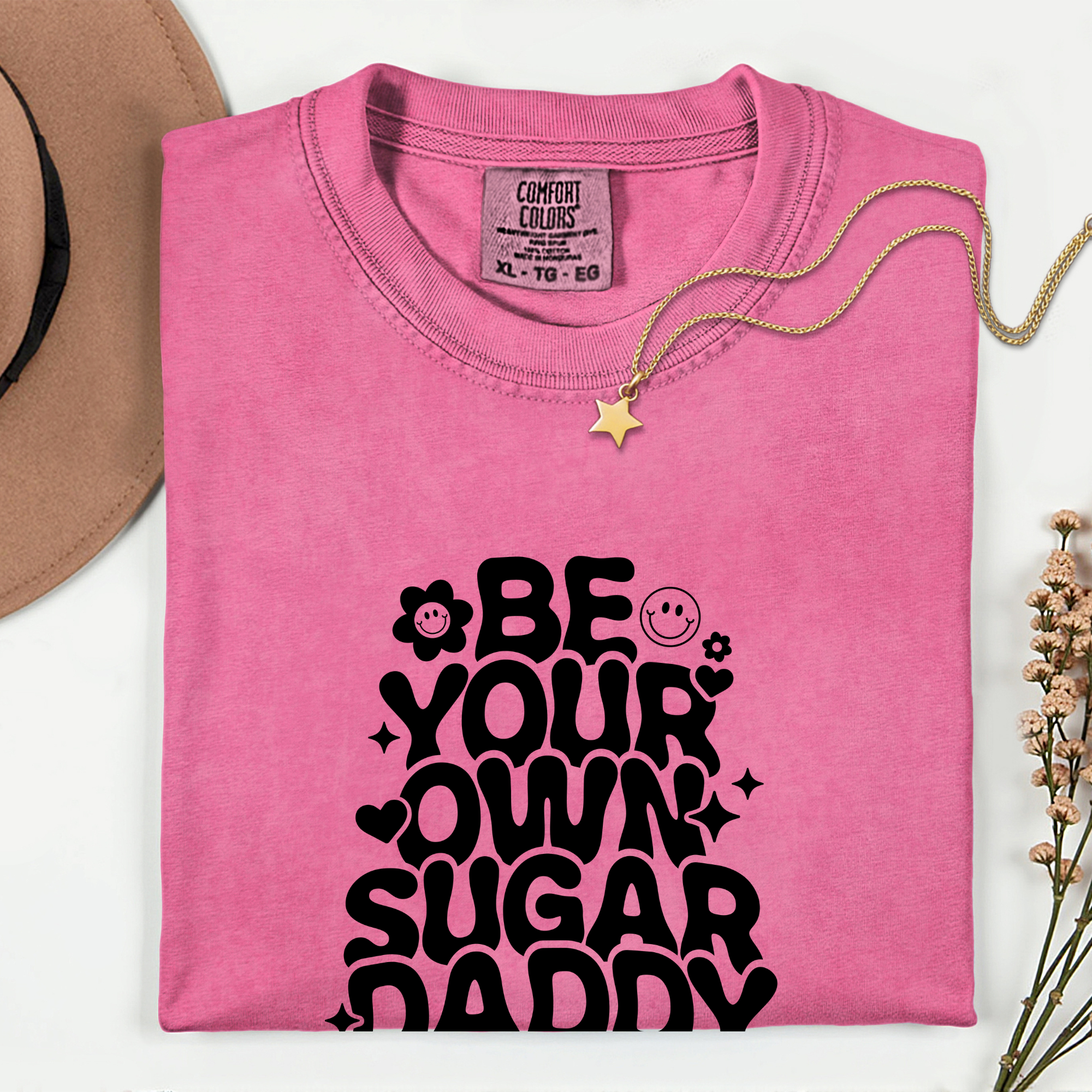 Pink t-shirt with 'Be your own sugar daddy' text on a white background